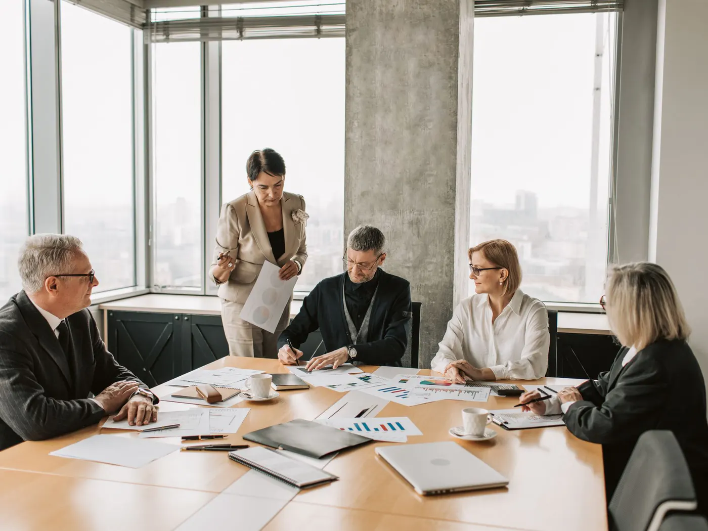 Business professionals reviewing reports and company documents around a meeting table